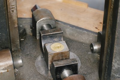 A metal cap that has just been stamped; it is still in the stamping machine.