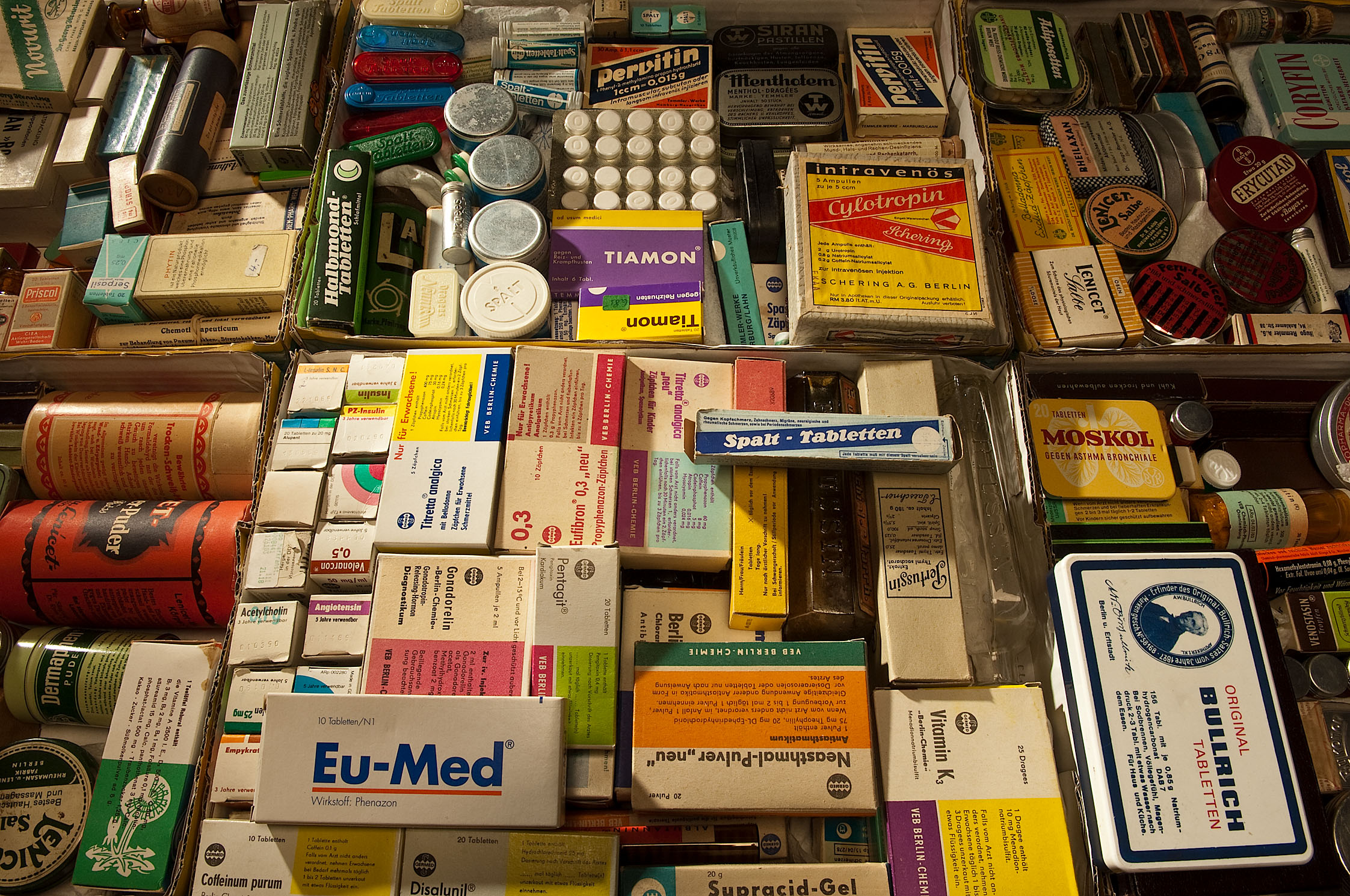 Historic medicine boxes, tubes and tins are packed tightly together. Among them are well-known brands of everyday headache and stomach remedies.