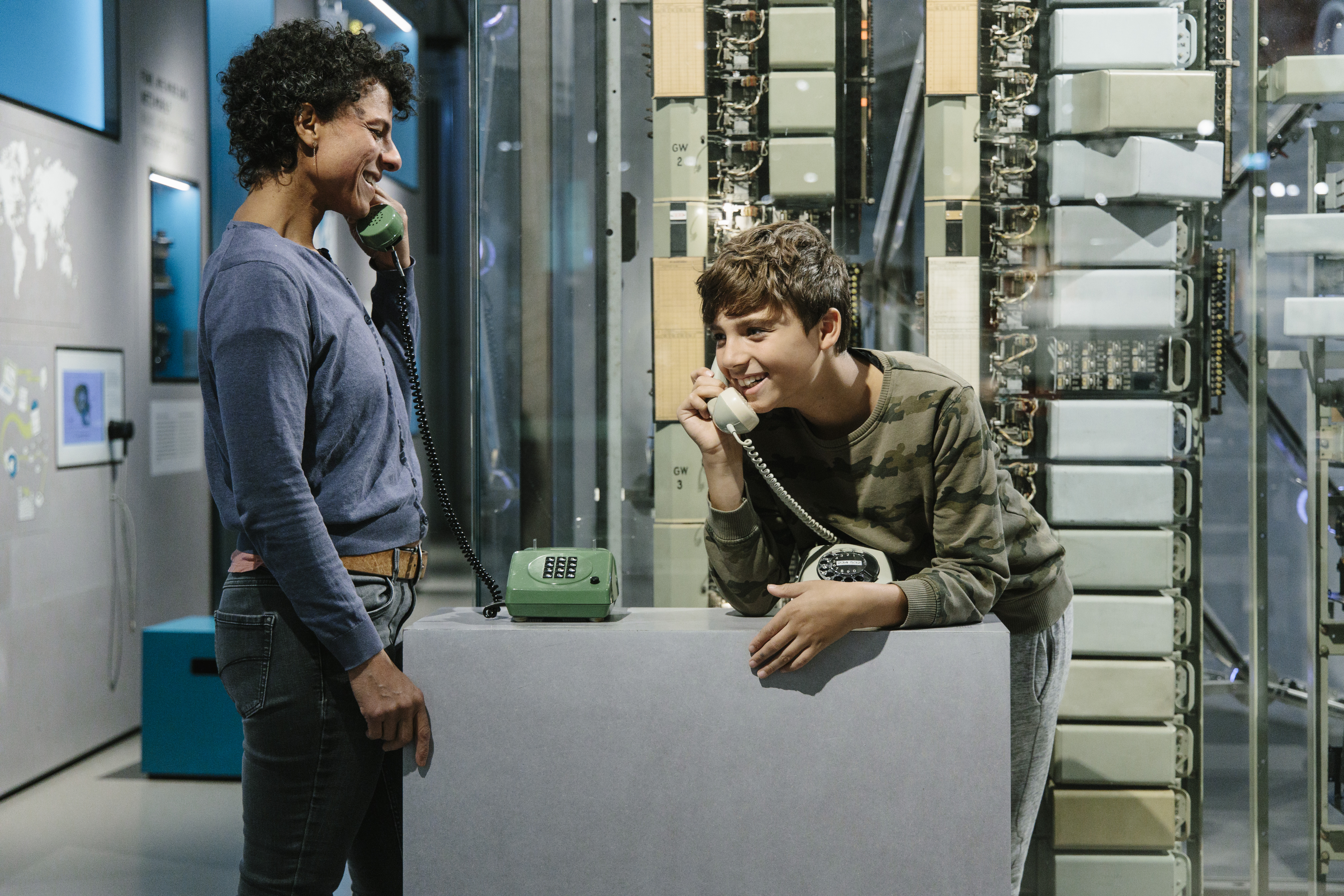 A woman and a boy are looking at telephones in the "Network" exhibition.
