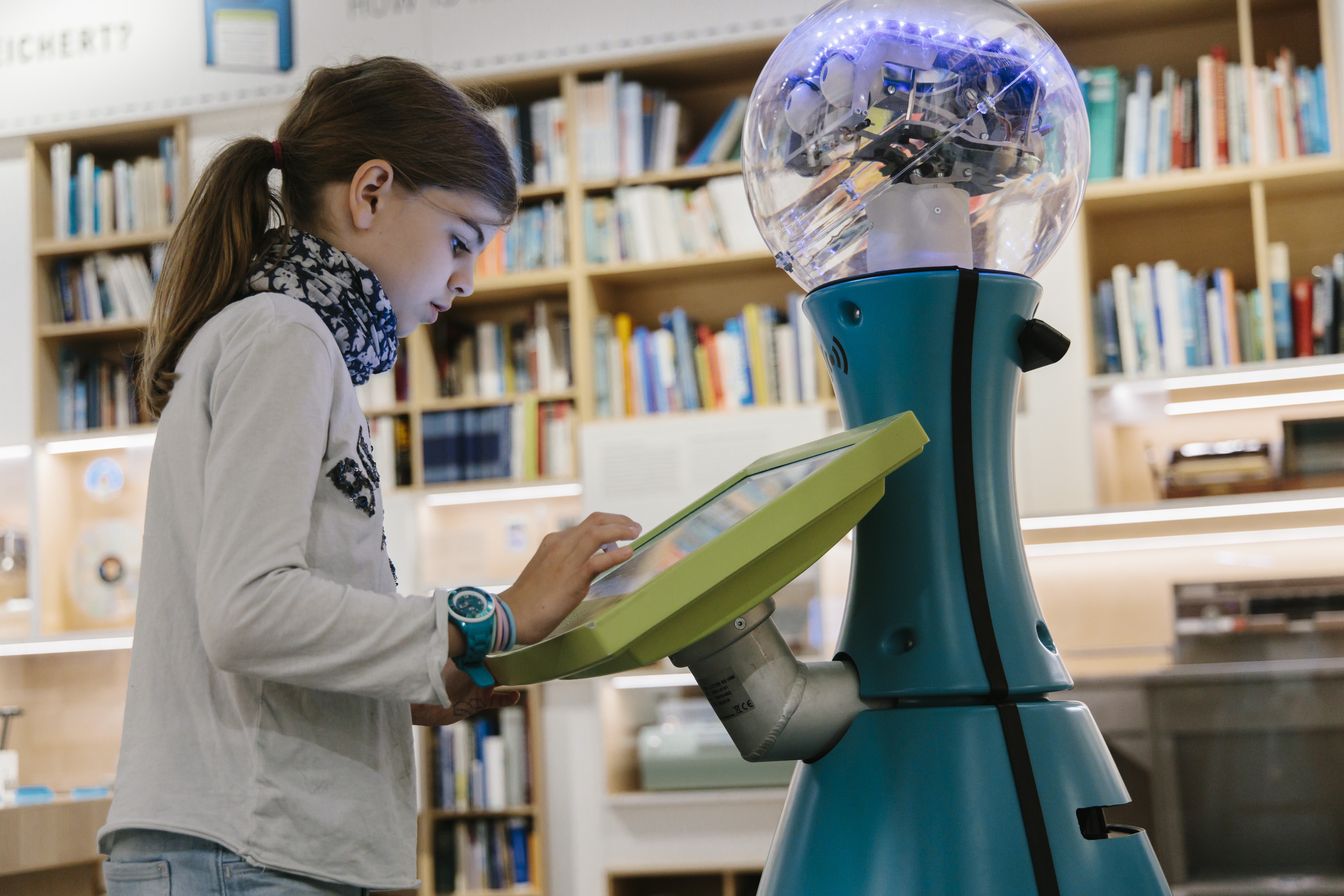 A girl is typing something on the screen of a humanoid robot.