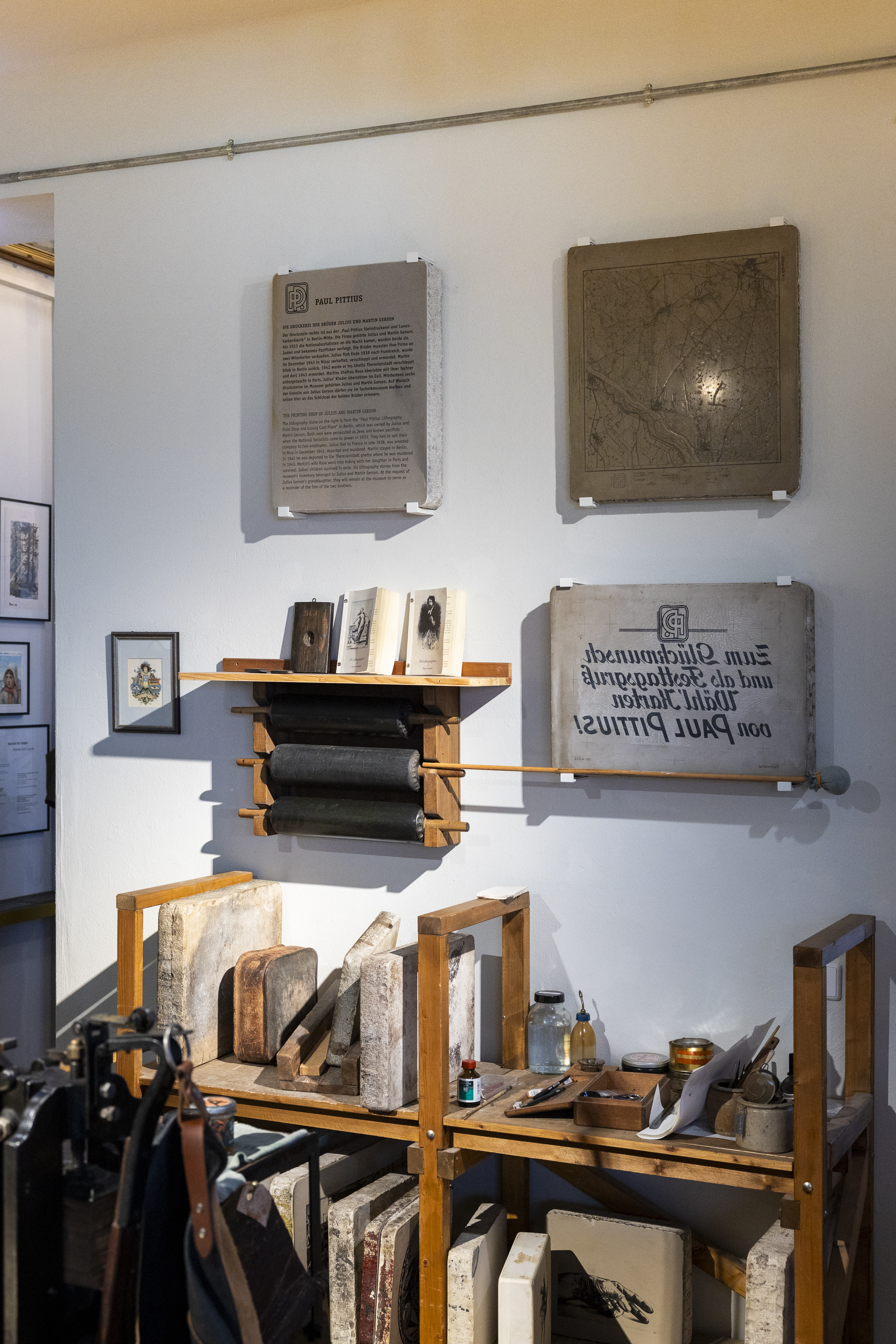 A view of an exhibition wall displaying printing stones and lithography equipment.