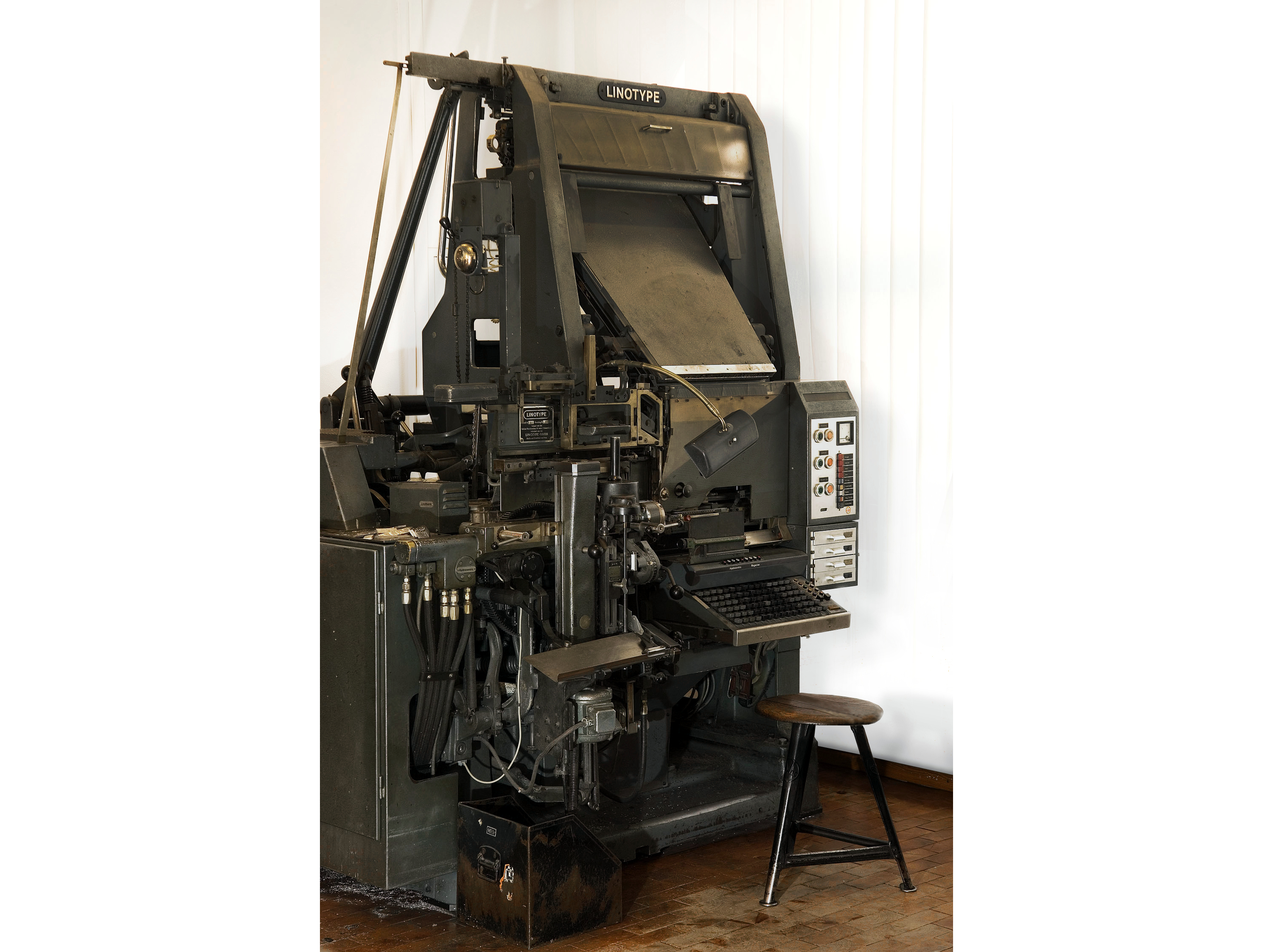  In the foreground of the machine, which is over two meters tall, you can see the typesetter's seat and the keyboard with its letters and characters. Above the keyboard is the type matrix magazine.