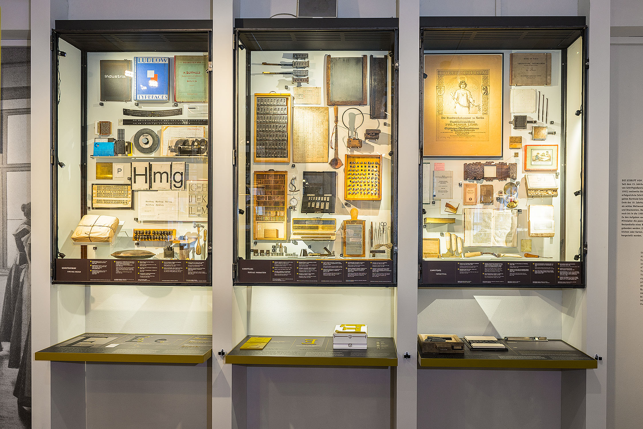 Three wall display cases showcase a wide variety of objects: books, tools, and dies.