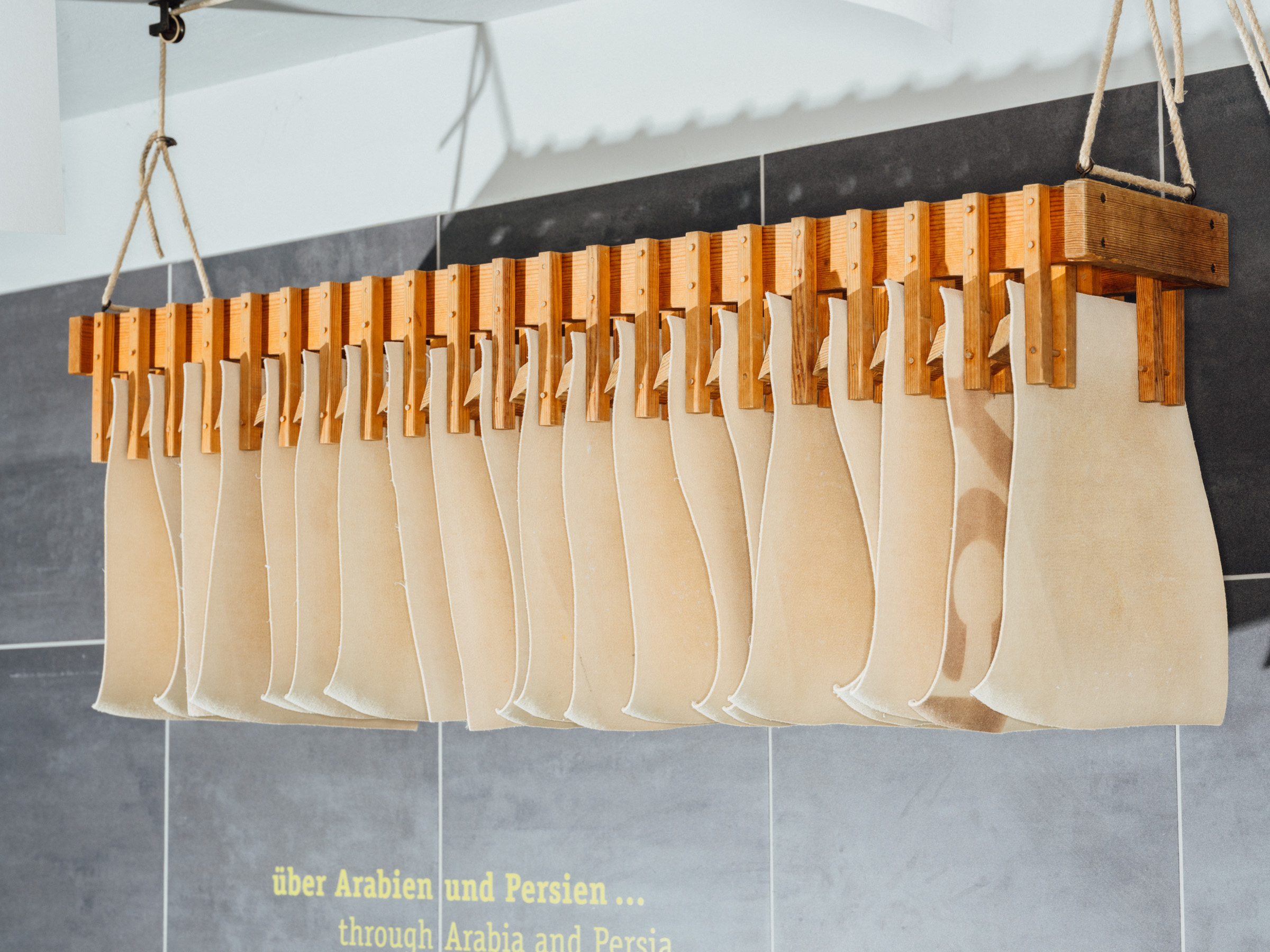 A stack of white sheets of paper is drying on a wooden rack.