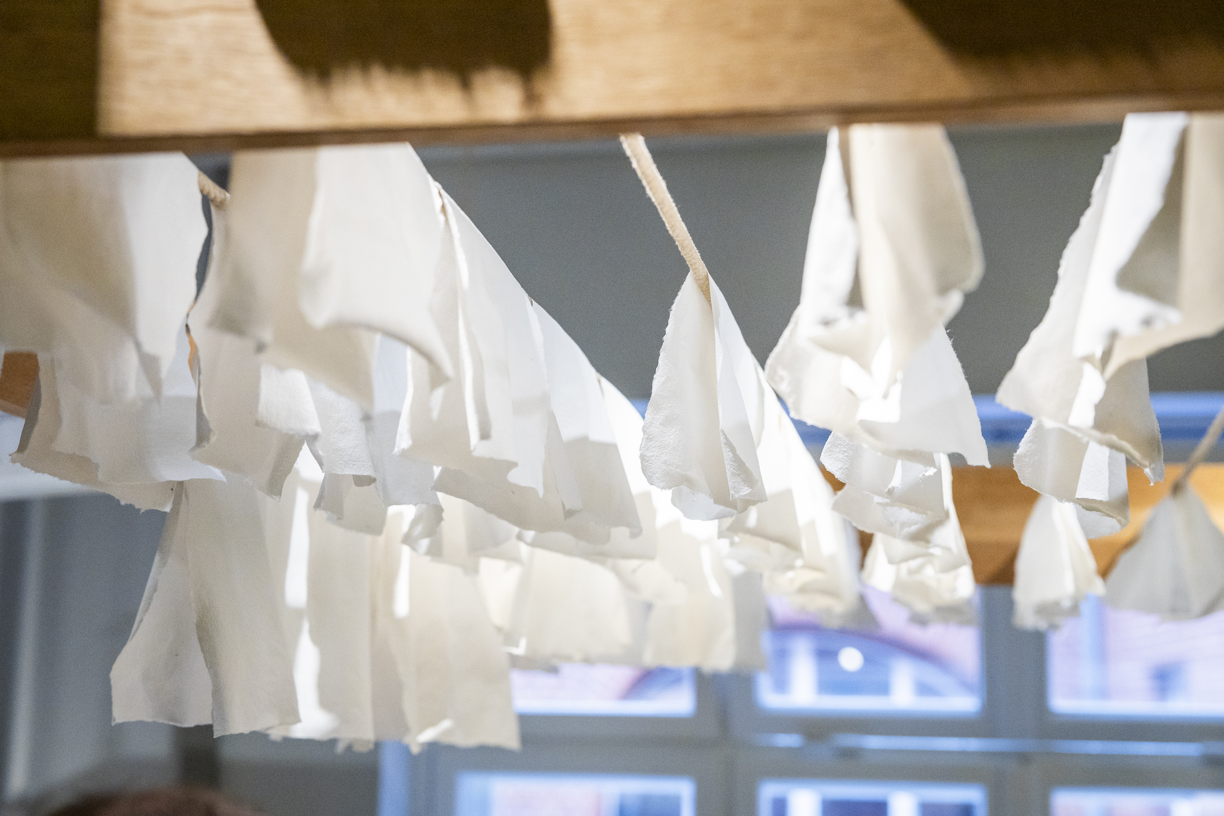 A stack of white sheets of paper is hanging on a wooden rack to dry.