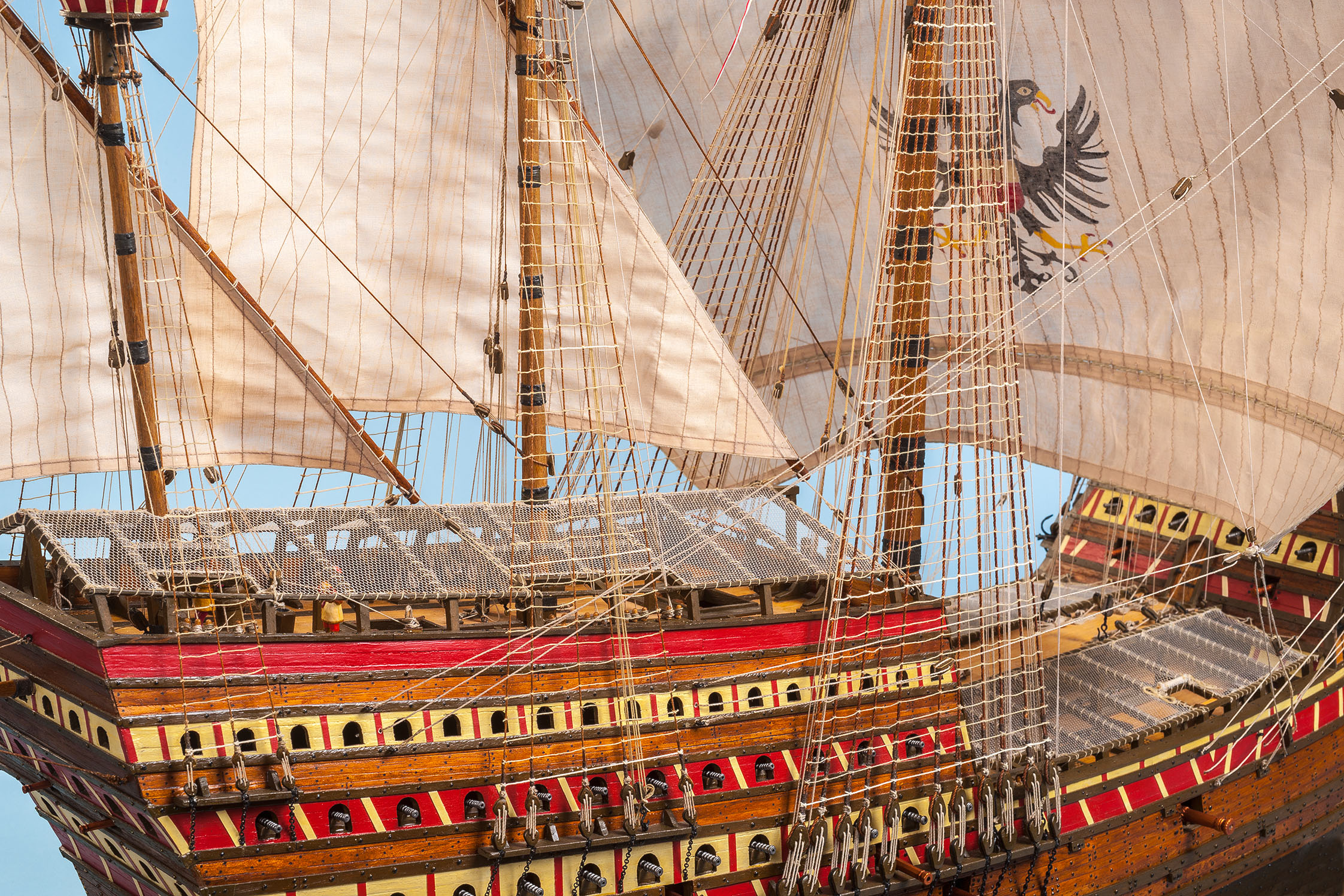 A close-up of a highly detailed ship model with its sails hoisted.  