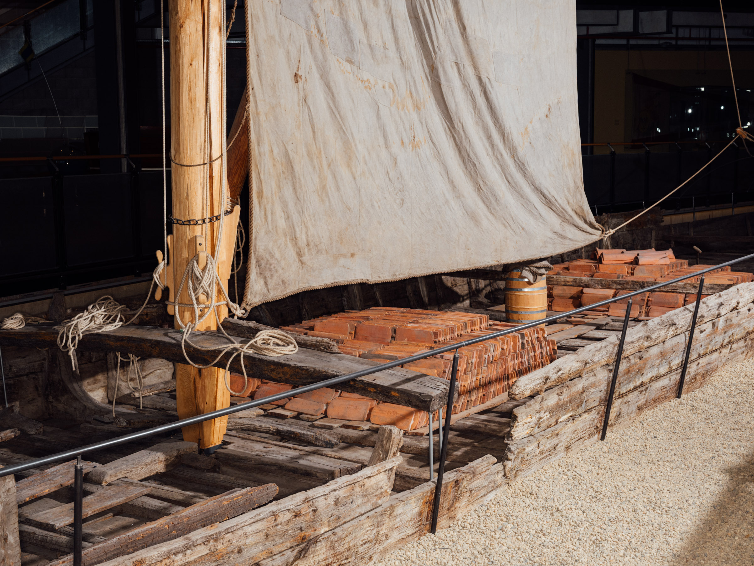 The Kaffenkahn is a wooden boat whose bottom planks curve upward to the waterline. The rudder and tiller can be seen at the stern of the slender boat.