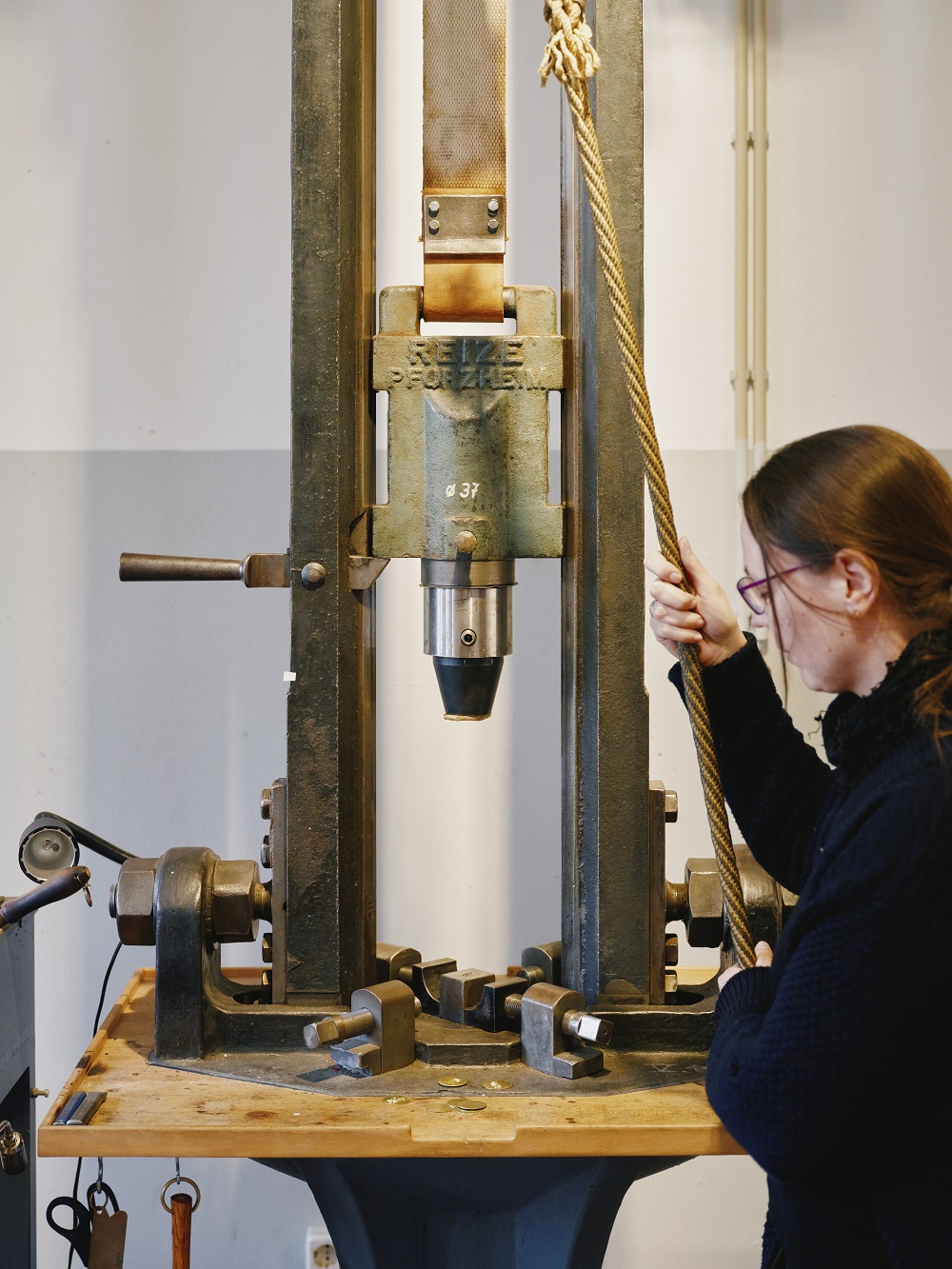 A woman is operating a machine that looks like a falling hammer.