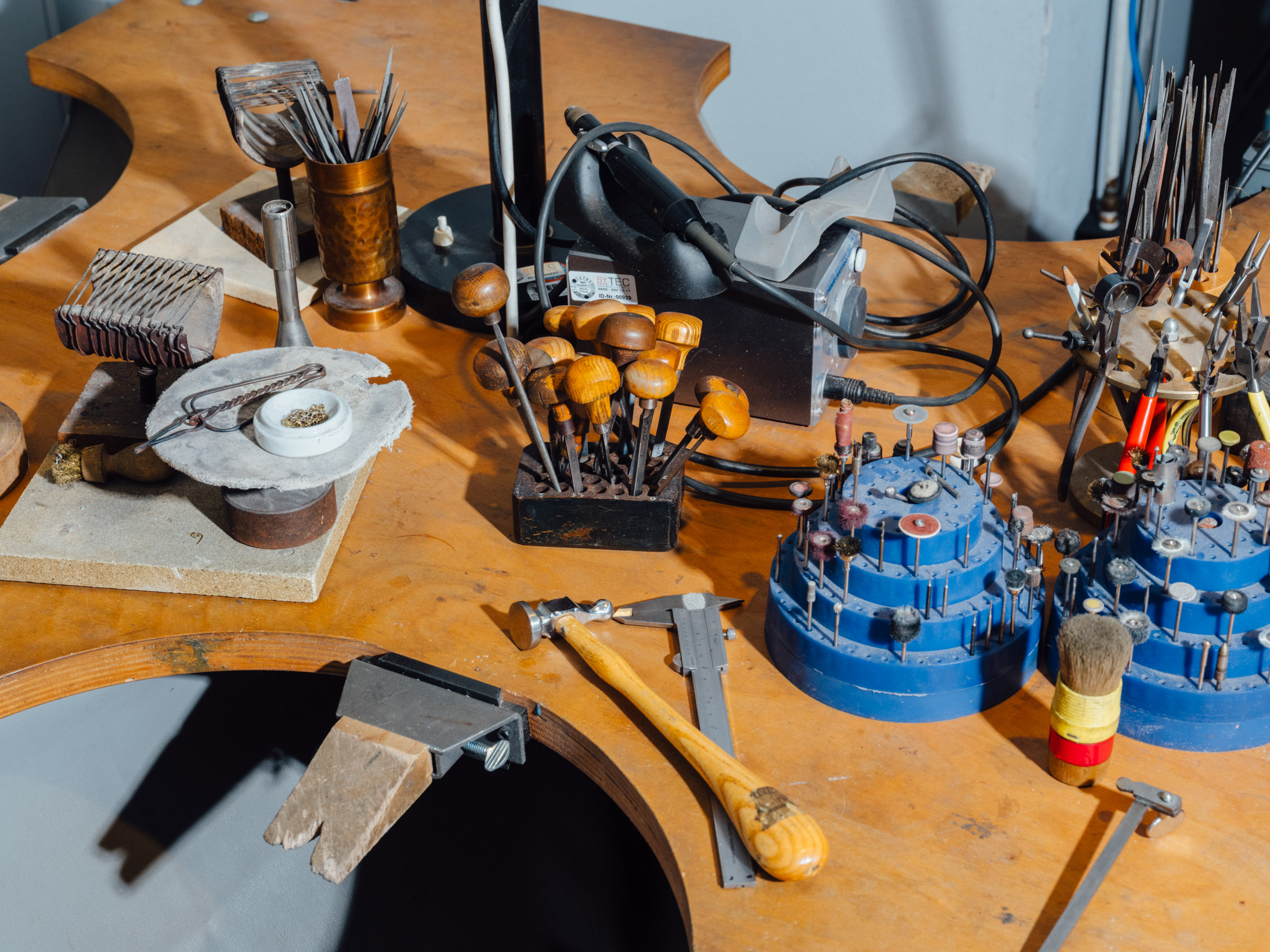 A workbench with various metalworking tools, including drill bits and pliers.