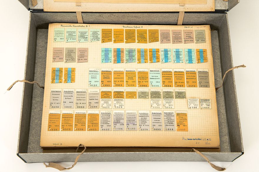 A view inside a cardboard box containing tickets of various colors lying side by side.